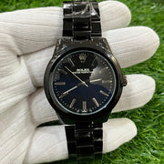 Black watch held in a white glove on green grass