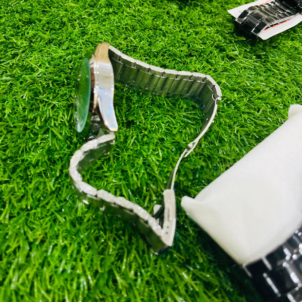 Metallic watch strap on grass with a bottle of glue